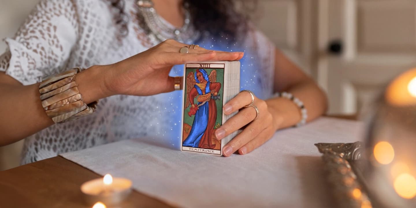 Femme tenant un jeu de tarot avec la carte Tempérance, prête pour un tirage spirituel dans un cadre apaisant – préparation d’un tirage cartomancie IdealVoyance