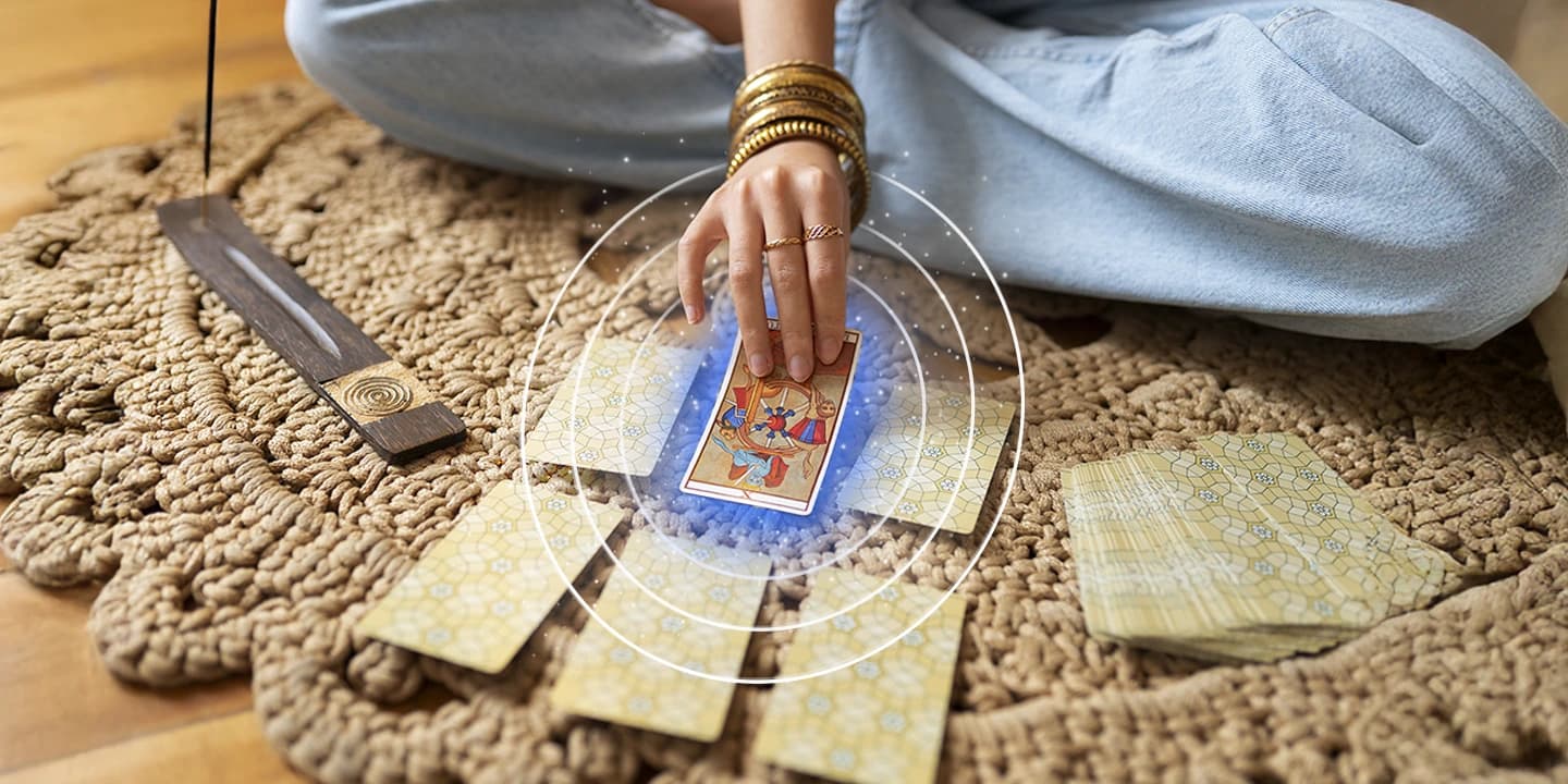 Main tirant une carte de tarot sur un tapis avec encens allumé, illustration de la carte dominante et de son rôle clé dans l’interprétation d’un tirage.