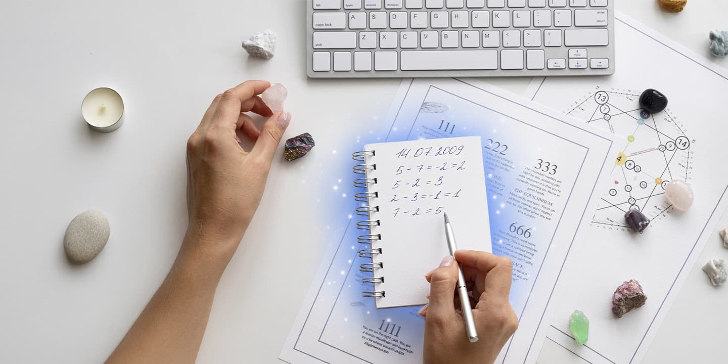 Bloc-notes avec des calculs numérologiques à partir d’une date de naissance, accompagné de cristaux et d’un clavier, illustrant le calcul du chemin de vie en numérologie