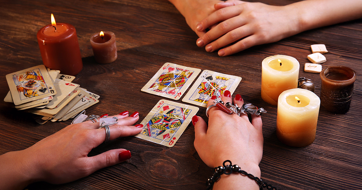 Tirage de cartomancie avec un jeu de 32 cartes posé sur une table, entouré de bougies, illustrant l’interprétation et la signification des cartes divinatoires.